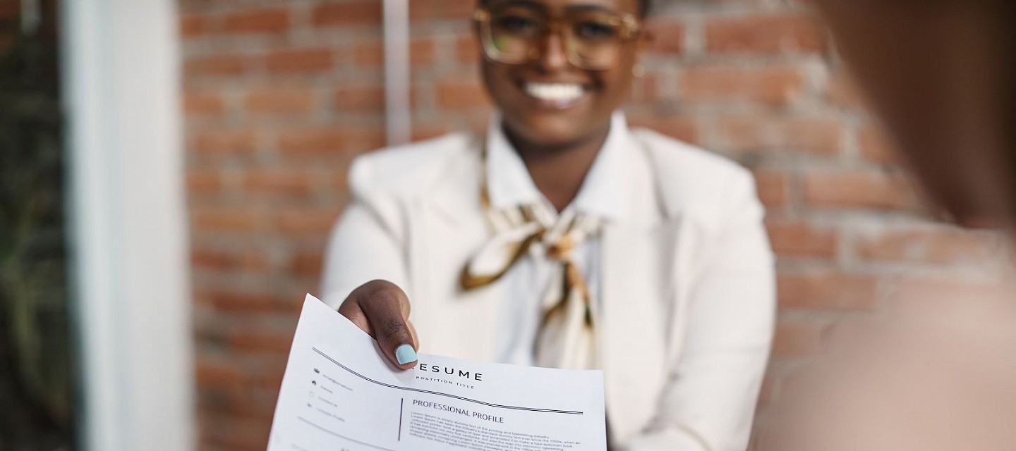 lady holding a cv in front of her and smiling